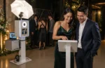 Guests using a Share Station touchscreen while the main photo booth remains available for the next group at an event.