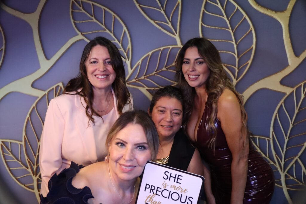 Guests smiling at a beÜtiful Pixels photo booth with a gold leaf backdrop at an Orange County event