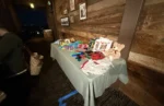 Interactive deluxe photo booth props including giant playing cards and feather boas set up against a rustic wooden wall at an Orange County venue.