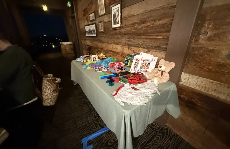 Interactive deluxe photo booth props including giant playing cards and feather boas set up against a rustic wooden wall at an Orange County venue.